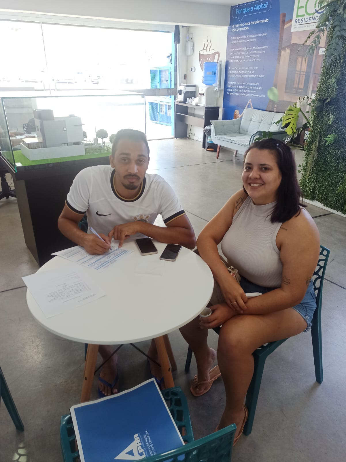 Cooperado 12 assinando o contrato da Alpha Cooperativa com sua esposa sentada ao lado