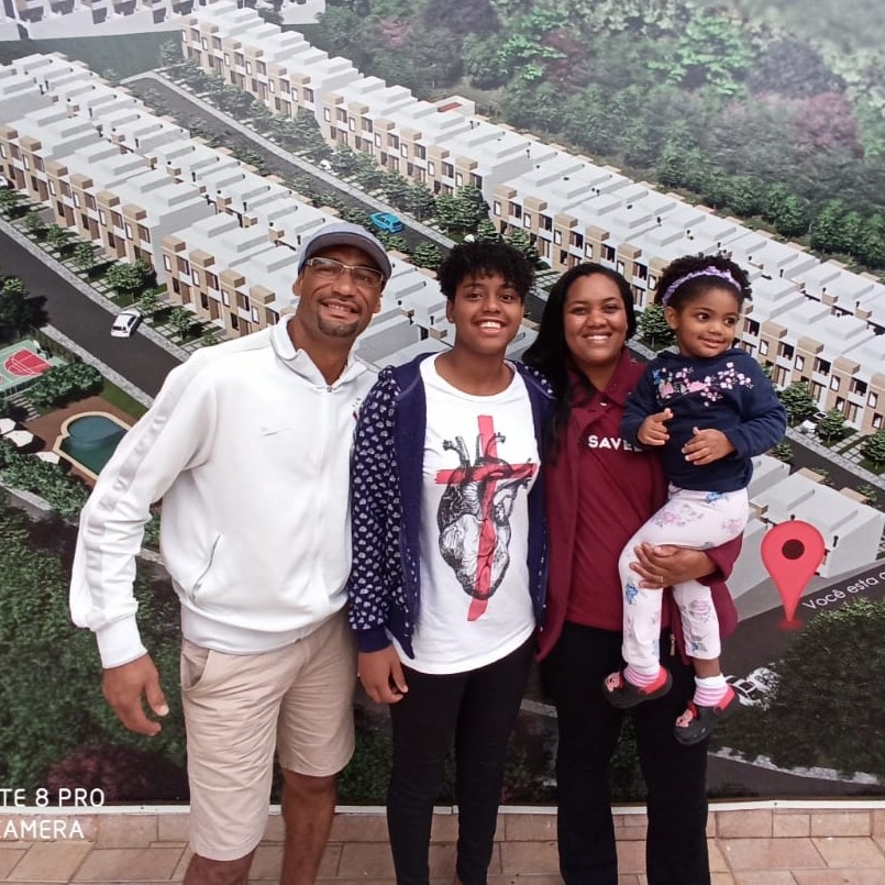 Cooperada Lívia segurando sua filha mais nova no colo ao lado de seu marido e sua filha mais velha