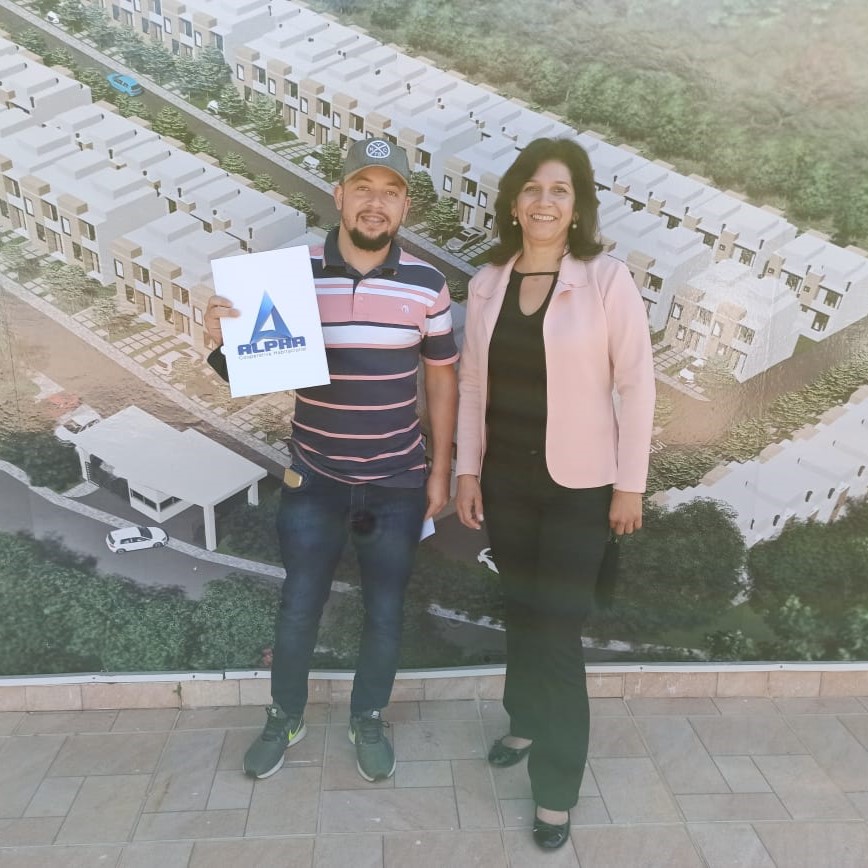 Cooperado André segurando o plano da Alpha Cooperativa ao lado da corretora Silmara