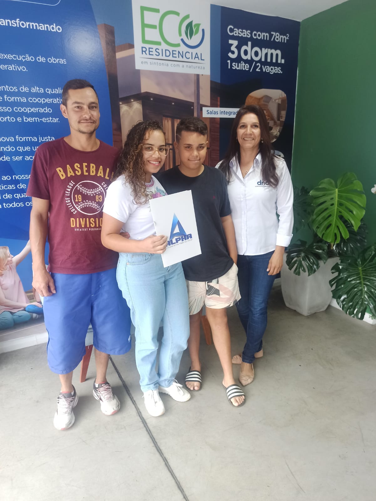 Cooperada 5 e sua familia segurando o planer com a sua família ao lado da corretora Silmara