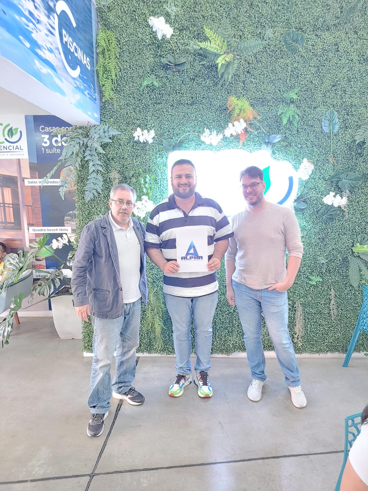Filha da cooperada 7 segurando o plano da Alpha Cooperativa com seus pais ao lado do corretor Clodoaldo
